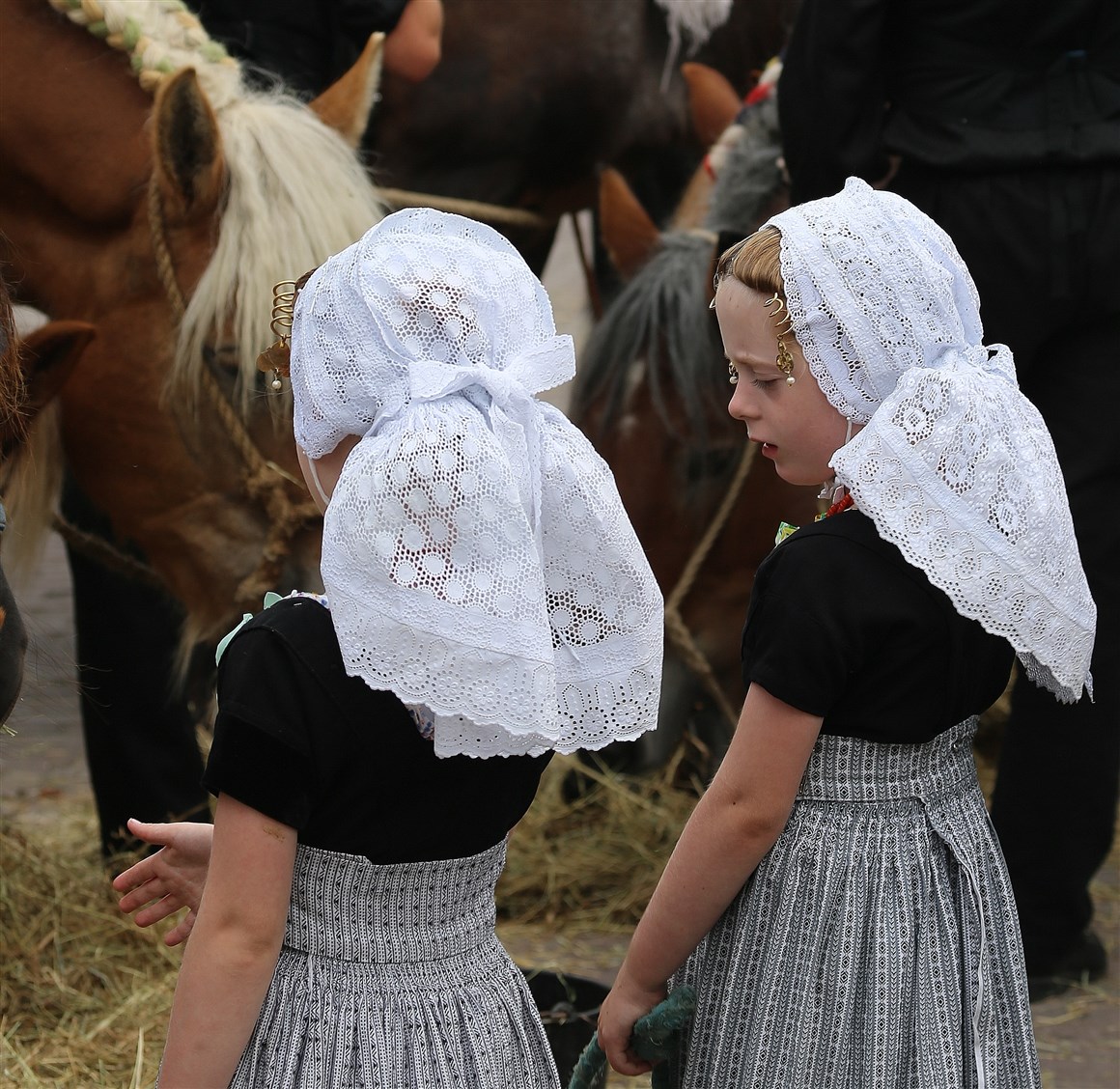 Twee meisjes in Walcherse dracht. Een grijs geruite rok, zwart top met korte mouwen en een witte muts.