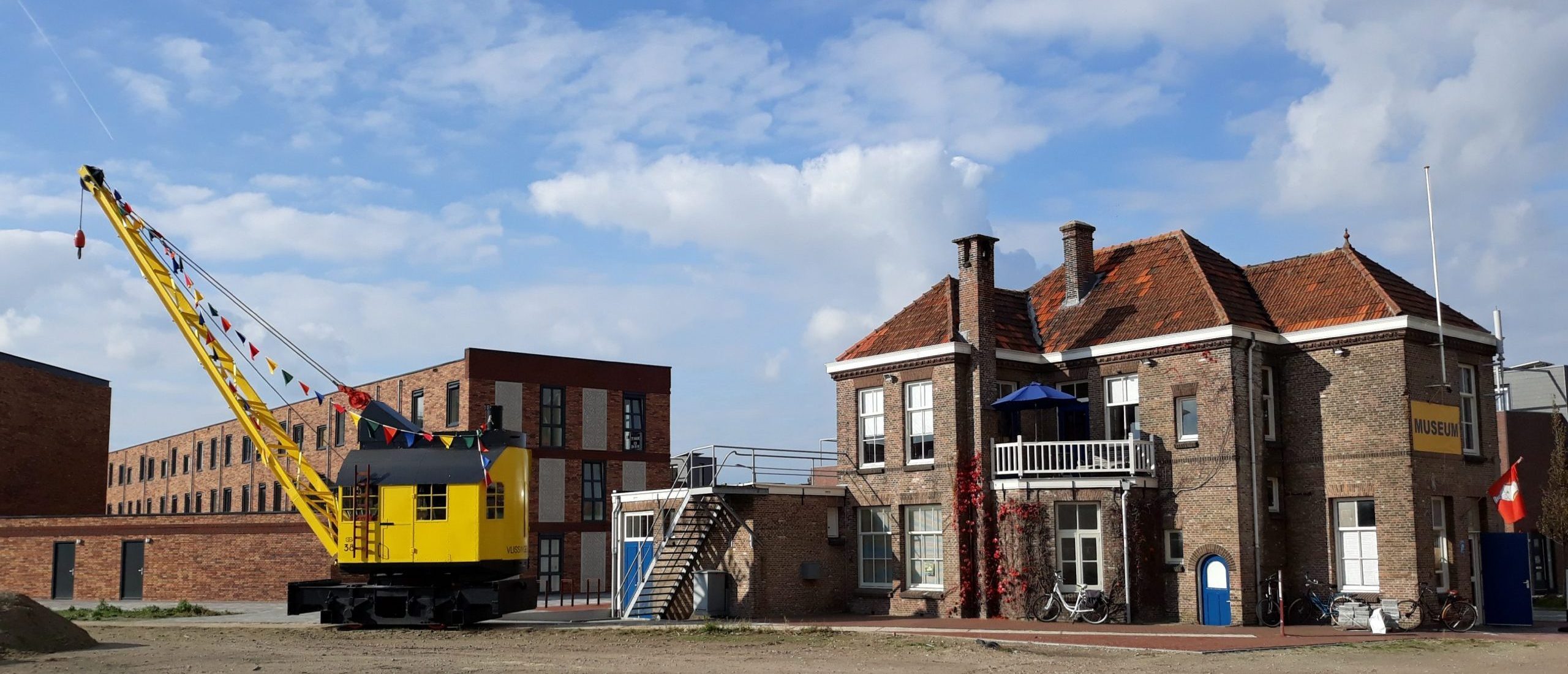 Gebouw Museum Scheldewerf in Vlissingen met daarnaast de historische gele stoomhijskraan Schelde 38.