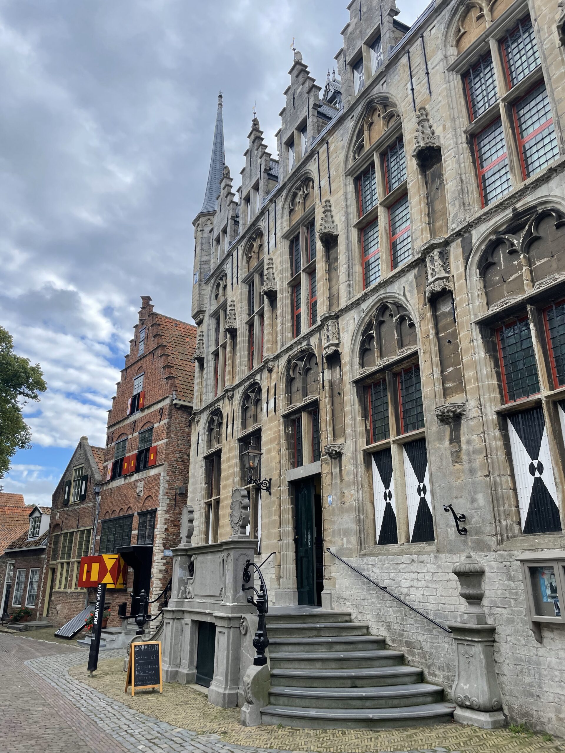 Het stadhuis is een laatgotisch rechthoekig gebouw met uitgekraagde kleine torens aan de voorzijde. De gevel van ledesteen is hier gefotografeerd vanaf de rechterkant, waardoor je enkel het rechtertrapje naar de ingang ziet. De gevel is rijk versierd en heeft verschillende glas in lood ramen. De ramen op de begane grond zijn gesloten, hiervoor zitten houten luiken.