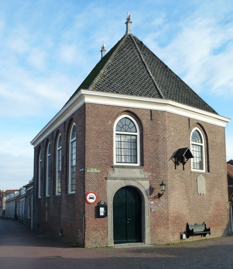 Voormalig hoekhuis omgebouwd tot kerk met boogvensters en houten gewelf. Hardstenen toegangspoort waarboven memoriesteen. Schilddak met zwanen op de hoekpunten. Er hangt ook een bel aan de muur en er is een bankje aan het gebouw gemonteerd.