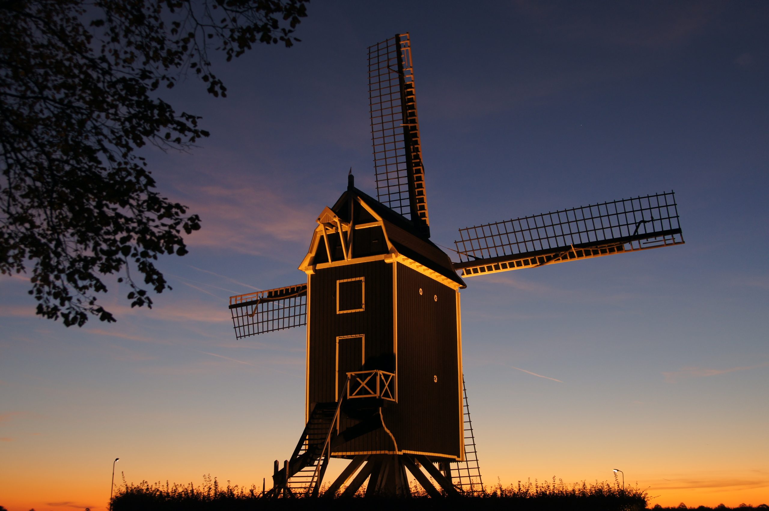 Een standerdmolen met een zwarte kast die wit is afgebiesd tijdens zonsondergang in Waarde.