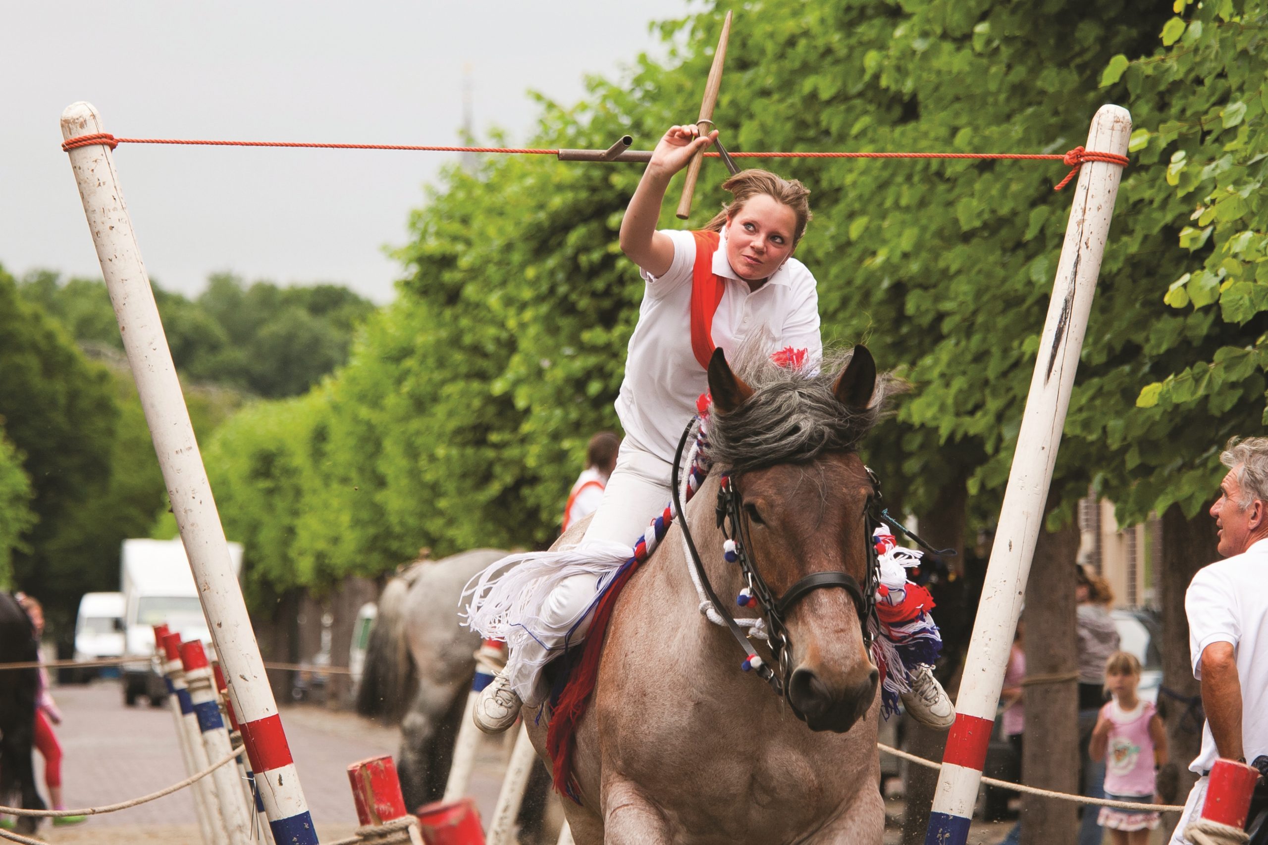 Een vrouw op een paard steekt tijdens het ringrijden een ring.